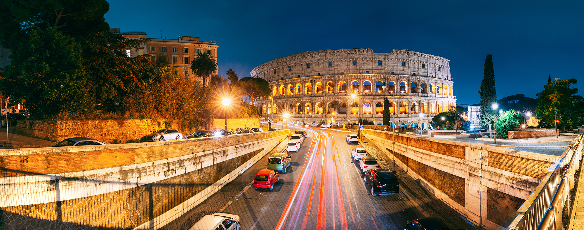 Rome, Italy. Colosseum Also Known As Flavian Amphitheatre. Traffic In Rome Near Famous World Landmark In Evening Time. Famous World Landmark UNESCO